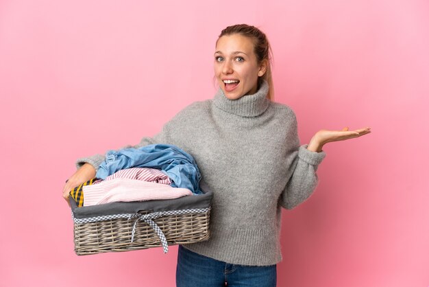 Young woman doing laundry isolated on pink