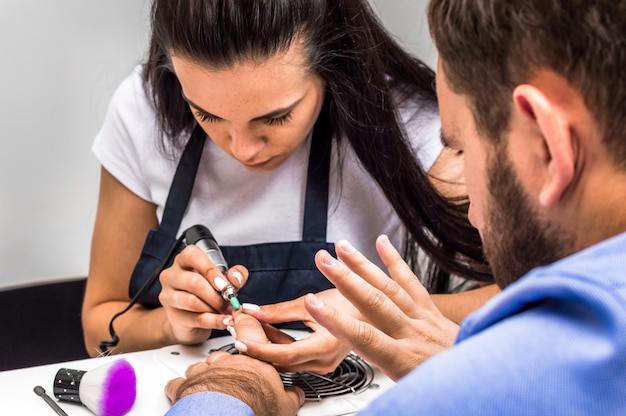 Young woman doing manicure to a man