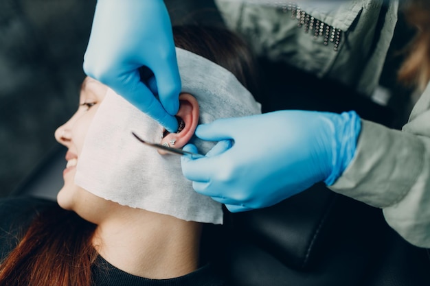 Young woman doing piercing at beauty studio salon