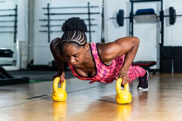Young woman doing plank with kettlebell exercising the muscles