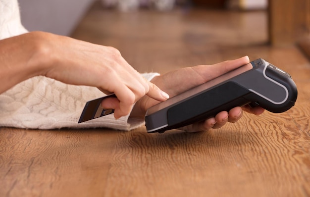 Young woman doing process payment with the bill or invoice on the POS cash terminal in a shop