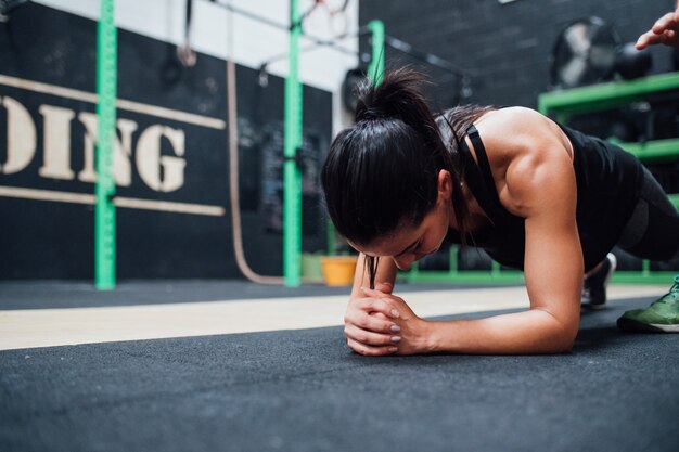 Young woman doing push ups training indoor gym