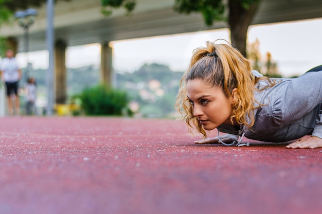 Young woman doing pushups on running track
