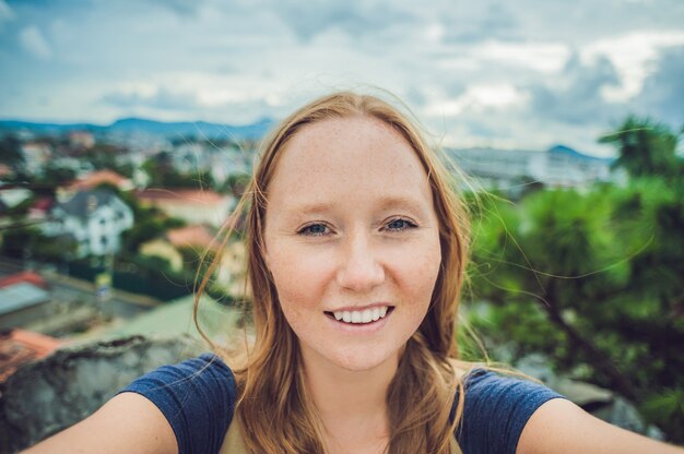 Young woman doing selfie on the of the city of Dalat