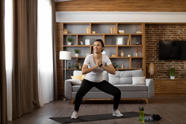 Foto giovane donna che fa squat durante l'allenamento a casa