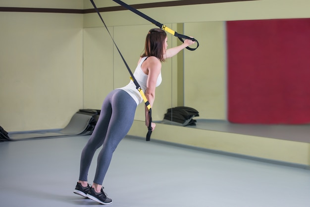 Young woman doing suspension training push-ups