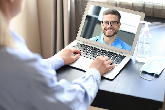 Young woman doing video conference with doctor on laptop. Coronavirus.