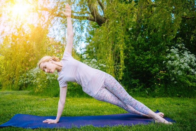 Giovane donna che fa yoga asana nel parco ragazza che allunga esercizio in posizione yoga donna felice e sana...