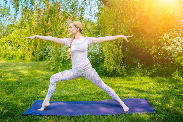 Young woman doing yoga asana in park girl stretching exercise in yoga position happy healthy woman