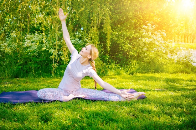 Giovane donna che fa yoga asana nel parco ragazza che allunga esercizio in posizione yoga felice e sana