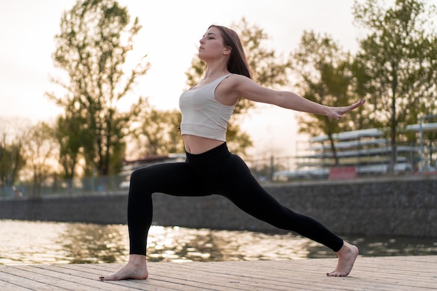 Foto giovane donna che fa yoga in riva al lago