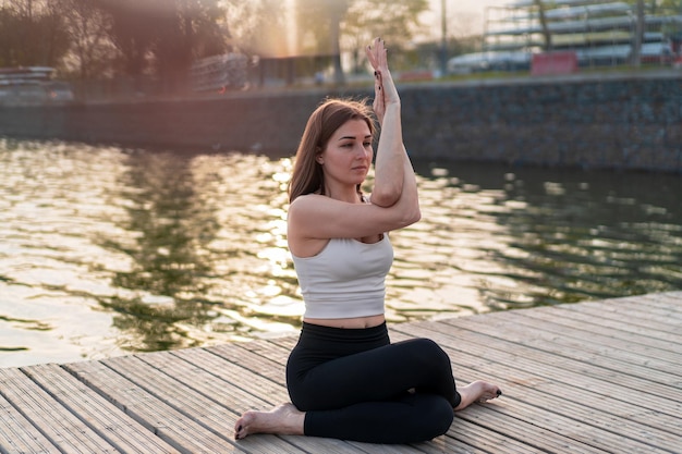 Giovane donna che fa yoga in riva al lago