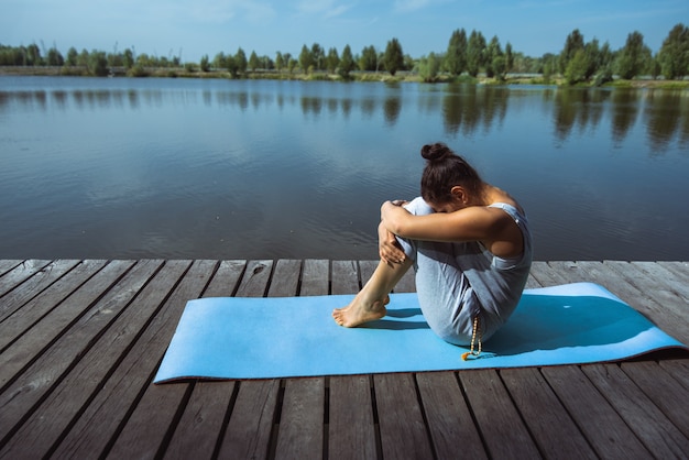 young woman doing yoga by the lake