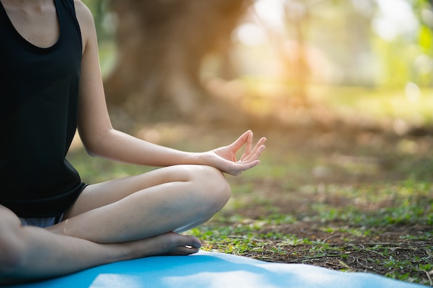 Giovane donna che fa esercizio di yoga all'aperto nel parco, concetto di yoga di sport