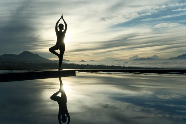 Young woman doing yoga exercise at the poolside