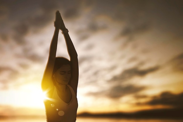 Young woman doing yoga exercise on seashore