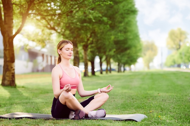 Giovane donna facendo esercizi di yoga nel parco