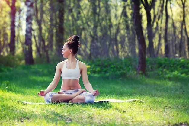 Young woman doing yoga exercises in the summer city park