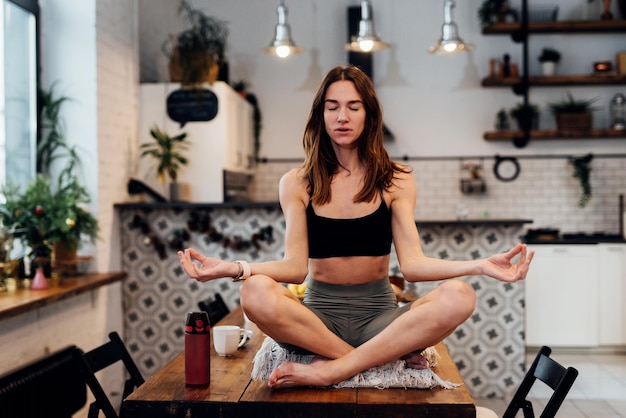 Young woman doing yoga at home in the lotus position