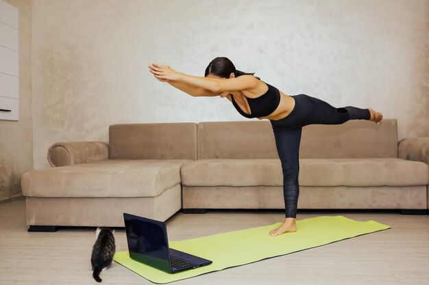 Young woman doing yoga at home. she practicing yoga, doing\
warrior iii exercise, virabhadrasana 3 pose