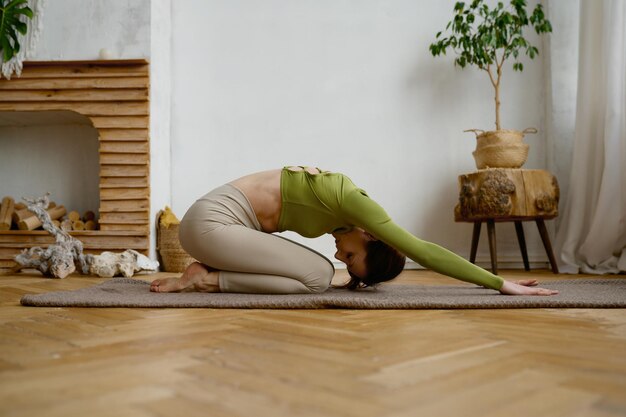 Young woman doing yoga stretching exercise on the floor wellbeing and healthy sport lifestyle concept