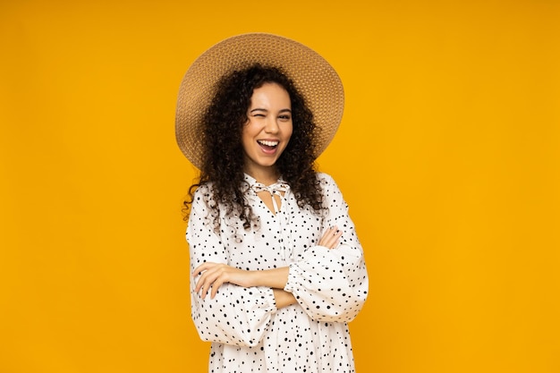 Young woman in dress and hat on yellow background