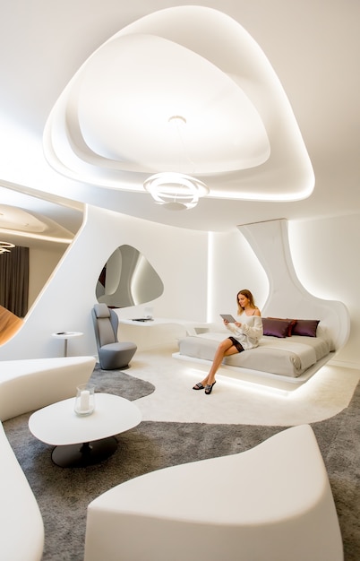young woman in dress using digital tablet in modern futuristic bedroom