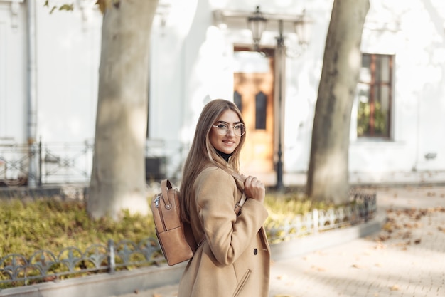 Молодая женщина в пальто и с рюкзаком гуляет по осеннему европейскому городу