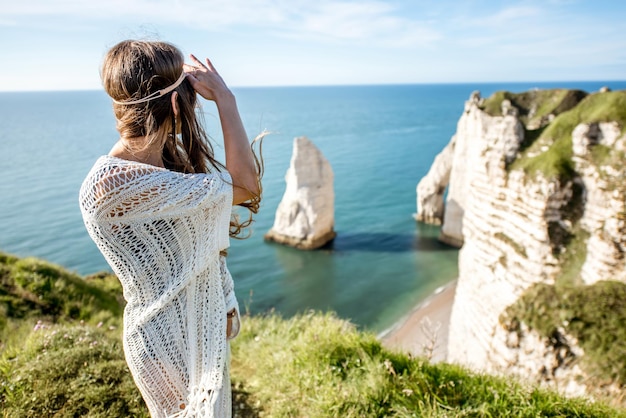 Молодая женщина, одетая в стиле хиппи, наслаждается природой на скалистом побережье с прекрасным видом на океан во Франции