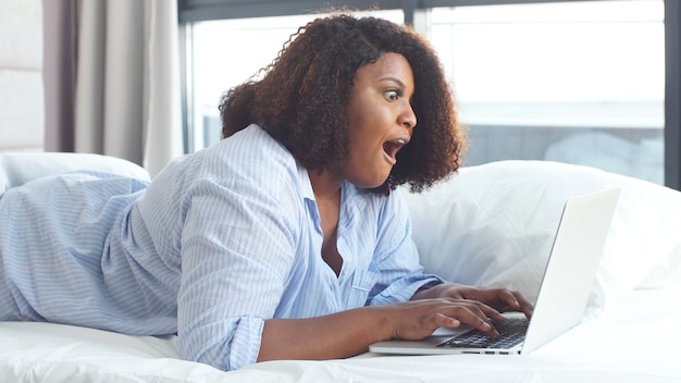 Young woman dressed in pajamas working at home on a laptop. Remote work. Self-isolation, quarantine