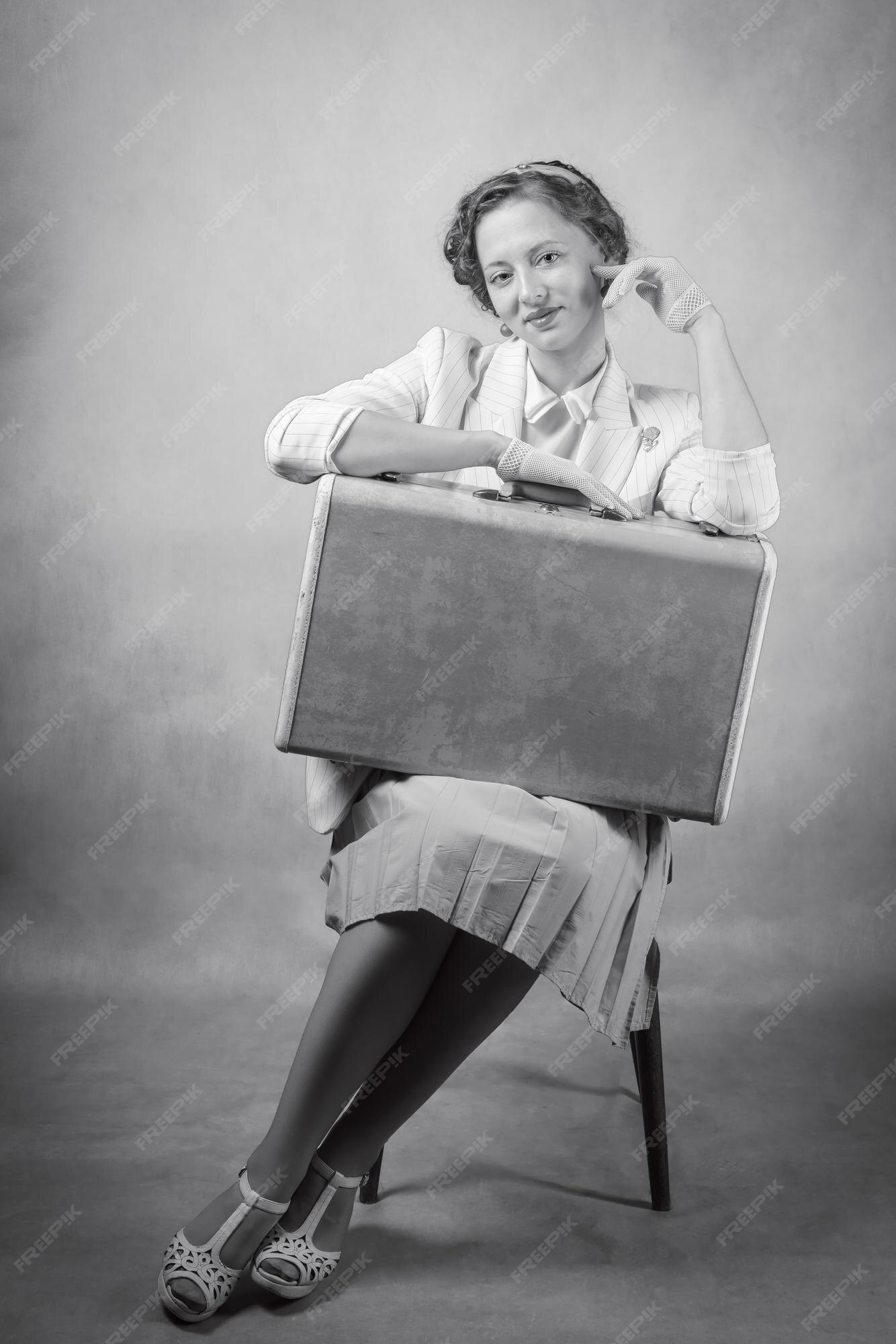 charming retro woman sitting on vintage suitcase and tv set while