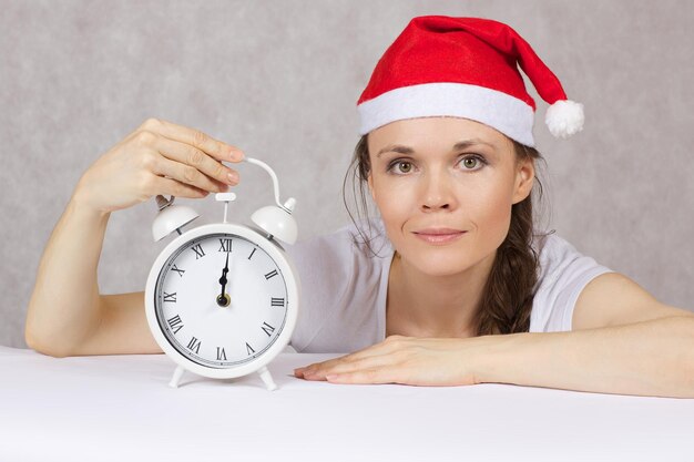 Foto giovane donna vestita con un cappello di babbo natale con una sveglia d'epoca.