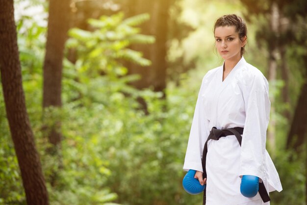 Young Woman Dressed In Traditional Kimono Practicing Her Karate Moves in Wooded Forest Area  Black Belt