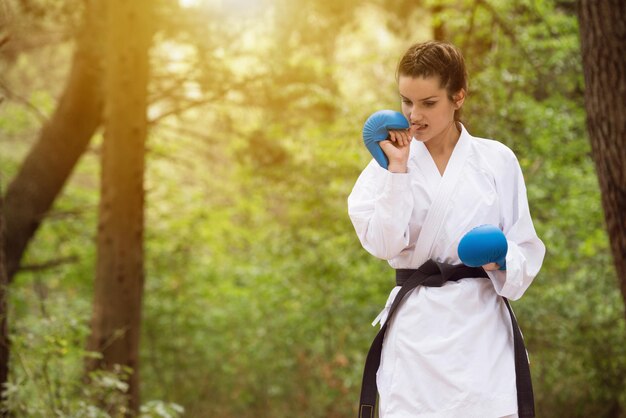 Young Woman Dressed In Traditional Kimono Practicing Her Karate Moves in Wooded Forest Area  Black Belt