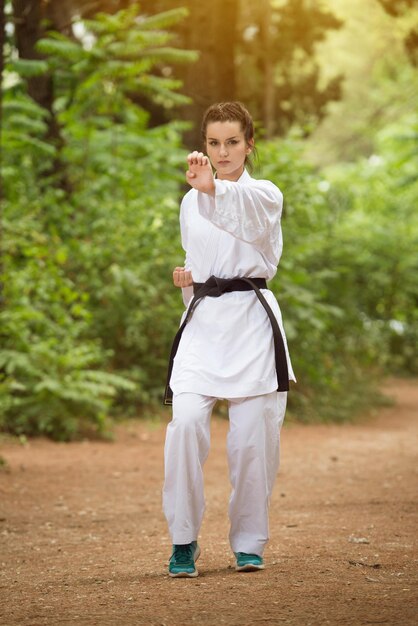 Young Woman Dressed In Traditional Kimono Practicing Her Karate Moves in Wooded Forest Area  Black Belt