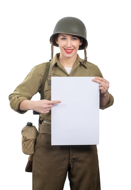 Young woman dressed in wwii military us uniform with helmet showing empty blank signboard with a copyspace