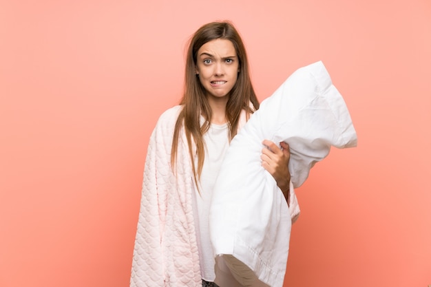 Giovane donna in vestaglia sopra il muro rosa che ha dubbi e con l'espressione faccia confusa