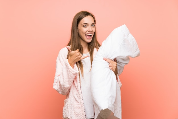 Photo young woman in dressing gown over pink wall making phone gesture