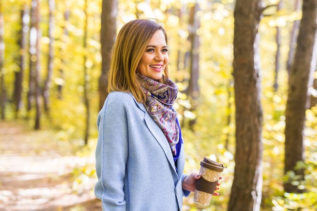 young woman drink coffee in autumn park