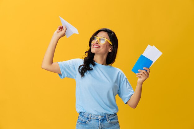 Young woman drinking bottles against yellow background