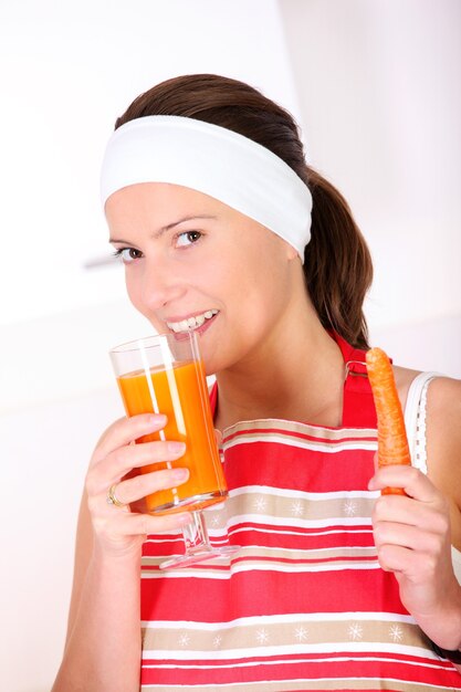 a young woman drinking carrot juice in the kitchen