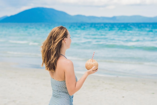 Young woman drinking coconut milk on beach.