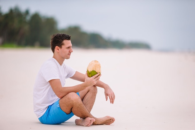 Latte di cocco bevente della giovane donna durante la vacanza tropicale