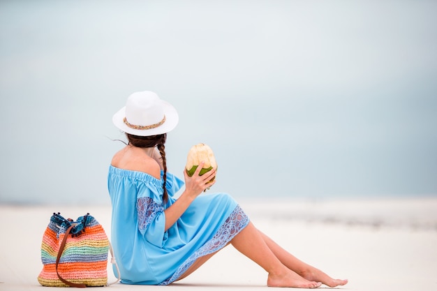 Young woman drinking coconut milk during tropical vacation