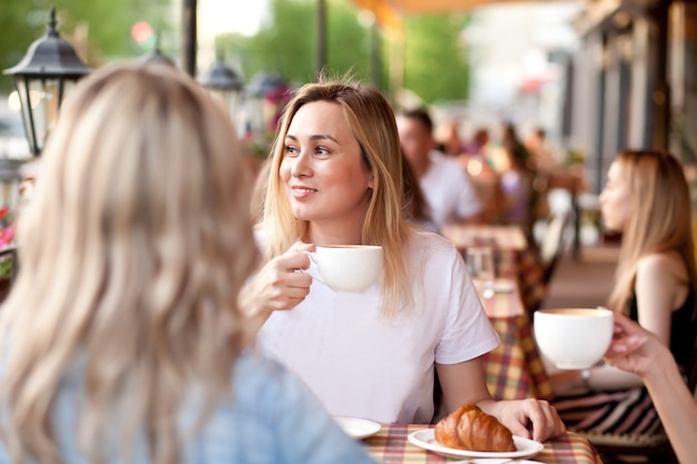 Молодая женщина пьет кофе на террасе кафе