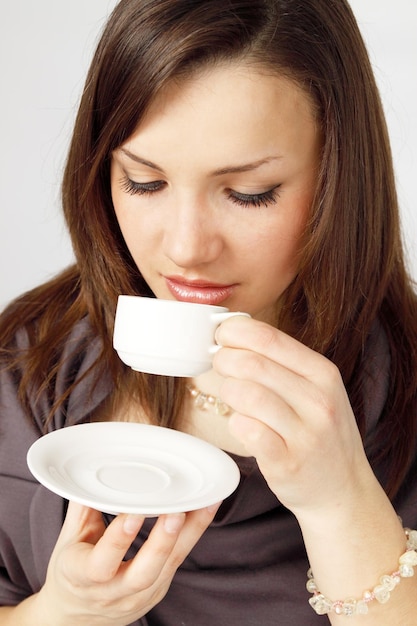 カップからコーヒーを飲む若い女性