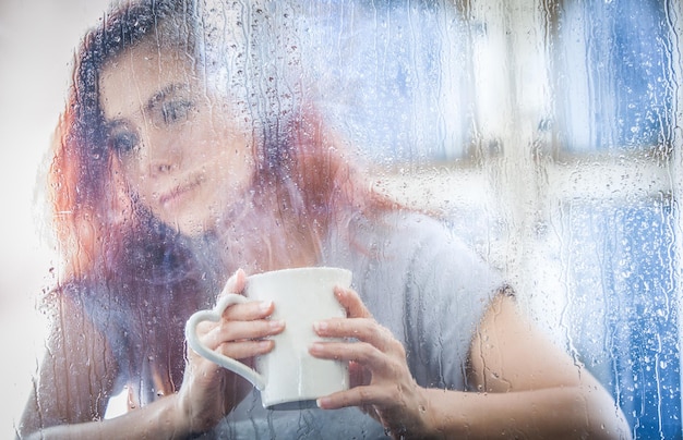 Photo young woman drinking coffee in glass window