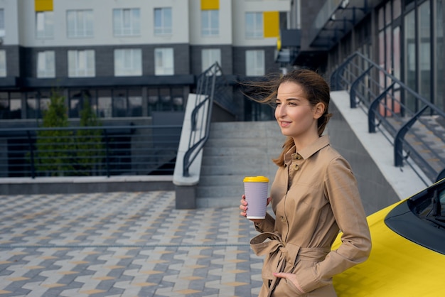 写真 通りでコーヒーを飲む若い女性