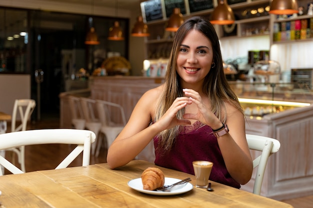 Молодая женщина пьет кофе и делает знак общения