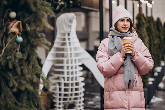 冬の通りの外でコーヒーを飲む若い女性